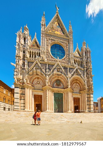 Low angle, vertical photo of the Cathedral of Santa Maria Assunta in Siena, white church against blue sky. Summer holidays in Tuscany, Italy. 