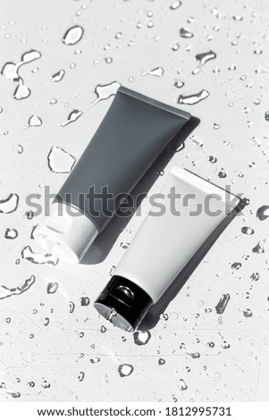 Two tubes of cream or body lotion, white and grey, on a white background with drops of water. Mock up. Treatment, spa, beauty, skincare, healthcare. Brand commercial. Product photo. Organic cosmetic. 