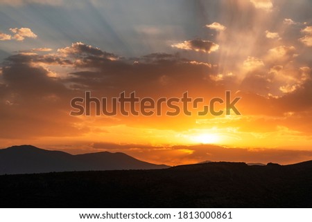 Beautiful bright sunset sky over the mountains silhouette . Dramatic orange clouds after sunset. Nature backgrounds. Golden sunset.