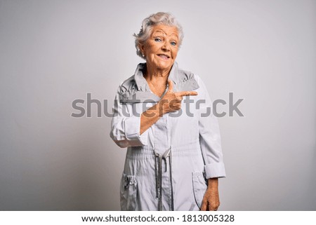 Senior beautiful grey-haired woman wearing casual jacket standing over white background cheerful with a smile of face pointing with hand and finger up to the side with happy and natural expression