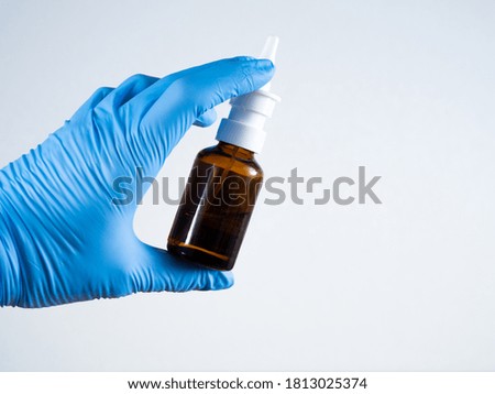 Hand in a blue medical glove keeping the medicine bottle on a white background. Close up. Copy space. 