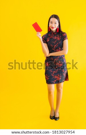 Portrait beautiful young asian woman wear chinese dress with Ang Pao or red letter with cash for chinese new year concept on yellow isolated background