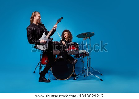 Full length photo two funky popular rock band perform new composition man play guitar woman drum drumstick enjoy punk night club tour wear leather jacket isolated bright color background
