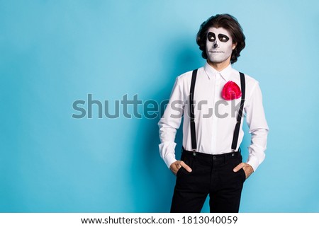 Portrait of his he handsome demonic creepy guy formal wear holding hands in pockets looking aside copy empty space event Santa Muerte isolated bright vivid shine vibrant blue color background