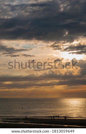 Sunset on the sea coast. Sandy beach at sunset, you can see the silhouettes of people. Summer sunset on the North Sea coast.