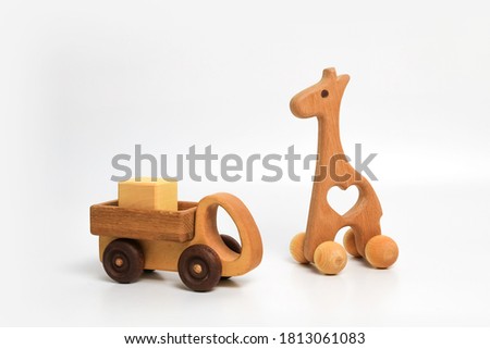wooden eco-friendly toy giraffe on wheels and a truck with a cube in the back on a white background, place for text Royalty-Free Stock Photo #1813061083