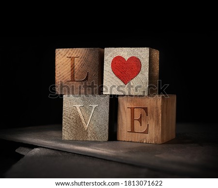 Creatively lit stacked cubes of rustic wooden blocks with the letters LOVE embedded. A concept image for St Valentine's Day. Generous accommodation for copy space if needed.