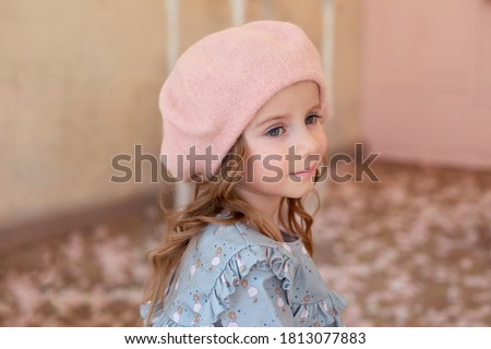 Pensive blond little girl with long curly hair. Closeup portrait of cute smiling girl in beret and dress on autumn street. Childhood concept.  dreaming french little girl. little lady French style. 