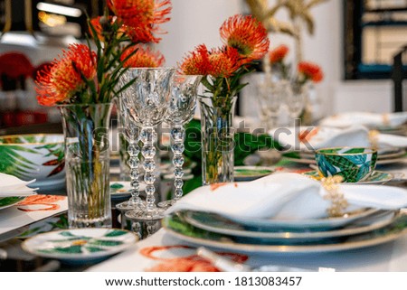 Tables set for an event party. Luxury elegant table setting dinner in a restaurant. Glasses and dishes. Empty glasses set in restaurant. Decorated with red flower.