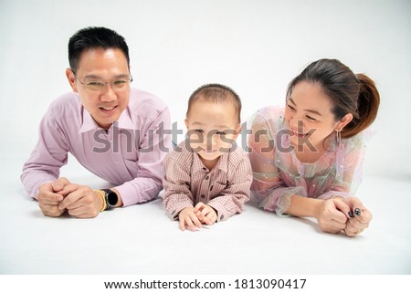 Thai-chinese  parent lie down and smile with their son