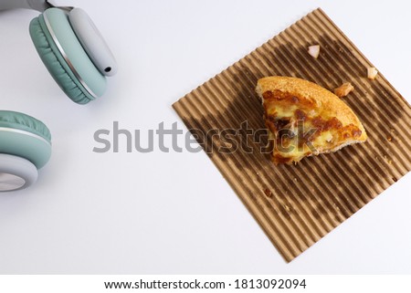 View from above of slice of pizza and headphone on white background