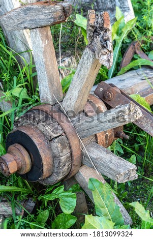 Vintage wreckage of wooden cart wheel in green grass.