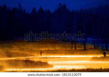 Silhouette of Fishing Flyfishing rod reel in river with golden sunlight Royalty-Free Stock Photo #1813113079