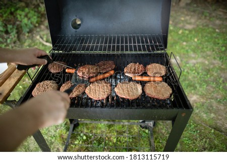 Person's hands checking meat temperature of burgers on backyard grill