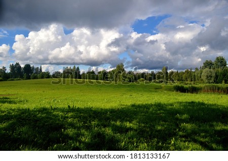 Black storm clouds during summer, Landscape with trees and meadows in the foreground in Latvia. Low clouds
