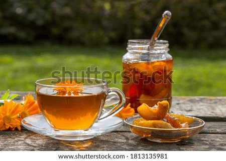 Tea with calendula and apple jam on a wooden table.