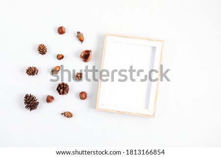 Autumn flat lay composition. Picture frame mock up, dried leaves and pine cones on light grey background. Autumn, fall concept. Mockup, top view, copy space