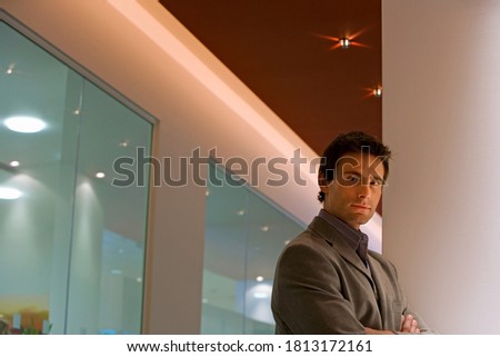 Side view of a businessman standing in modern office with arms folded with copy space.