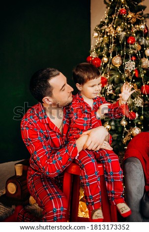 Cheerful father hugs his little son near the Christmas tree