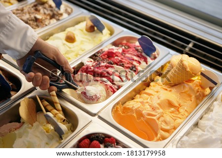 Close-up of a man scooping ice cream from tub in an ice cream parlor. Royalty-Free Stock Photo #1813179958