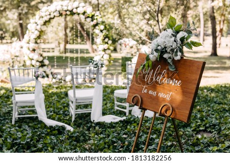 Wooden board with Welcome to our event text at a wedding on aisle background.