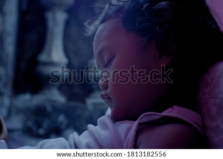 A girl from Minangkabau (Asian) ethnicity is sleeping soundly while sitting down after being tired of playing at home.