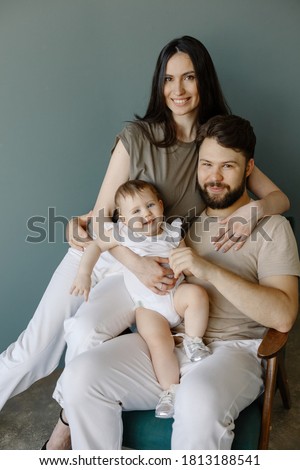 Portrait of young happy man and woman holding newborn cute babe dressed in pink clothing. Caucasian smiling father and mother embracing tenderly adorable new born child. Happy family concept