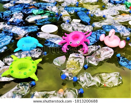 pollution of the environment. plastic bottles in water and inflatable toys.
 Inflatable pink flamingos, green turtle, blue fish, raspberry crayfish among plastic garbage