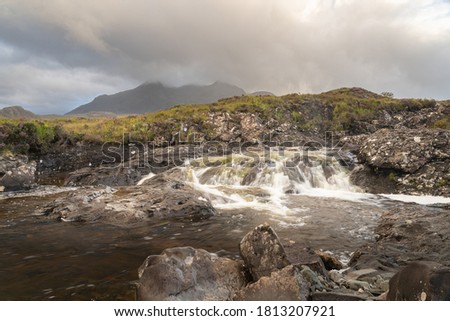 Beautiful Sligachan waterfalls on the Isle of Skye in the Highlands of Scotland, the Cuillin mountains rising behind lit by sunset
