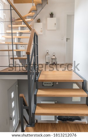 Staircase of a private house with modern stairs. Steel frame with wooden steps, white and gray walls, harmonious color concept. Vertical stock photo.