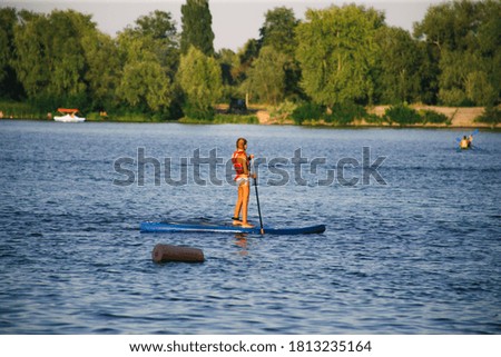 Young beautiful woman in a bikini on a SUP board in the river