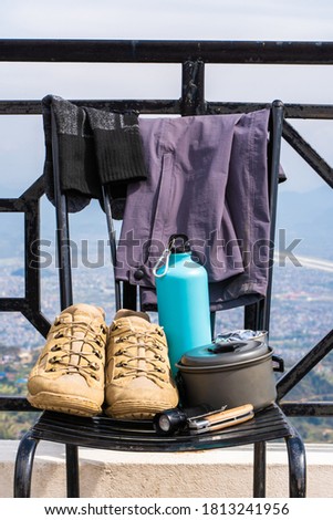 Trecking or hiking equipment - boots, socks, pants, folding knife, water flask, kettle pot and flashlight. Outdoor activity concept. Still life close up stock photo.