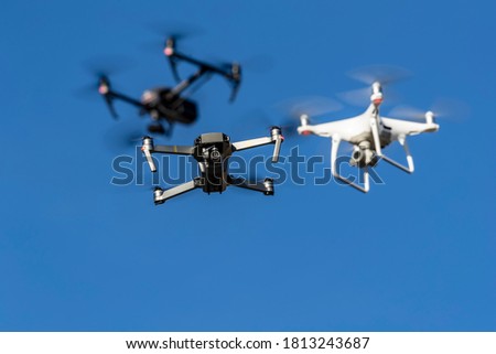 A group of drones fly through the air against a blue sky