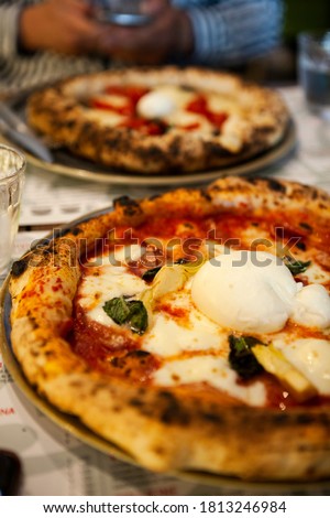 Delicious Italian pizza with mozzarella cheese, prosciutto, funghi (mushrooms) on the table at the local restaurant in the middle of Rome city, Lazio, Italy. European fast food and traditional dishes. Royalty-Free Stock Photo #1813246984
