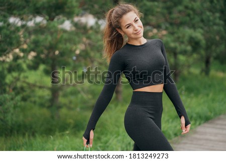 portrait of a brunette woman of European appearance in sports comfortable clothes black color. smiling and posing for the camera. good mood