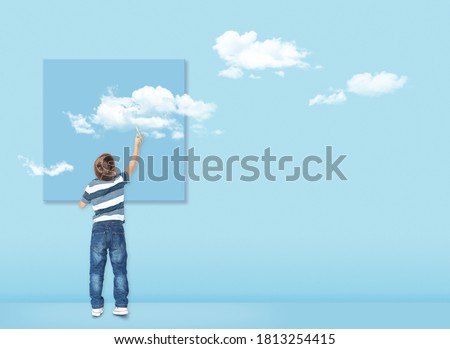 Boy draws with a brush white clouds. Concept image about freedom of mind and thinking outside the box. Freedom concept. Free your mind.