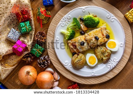 Cod loin (Lombo de bacalhau) recipe baked in olive oil, with potatoes, broccoli, boiled egg and black olives. Typical dish of Portugal. Christmas decoration. Top view.