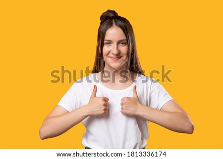 Like gesture. Good job. Happy young woman showing thumbs up. Isolated on orange copy space. Confidence and success. Approval sign
