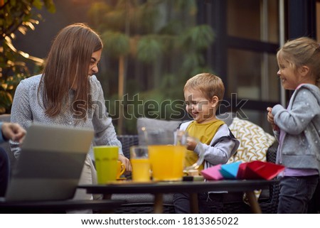 young mother with her son and daughter laughing and having fun, sitting outdoor