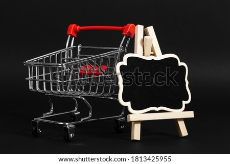 A frame on a stand and shopping cart on a black background, a blank for the design, concept. Copy space.