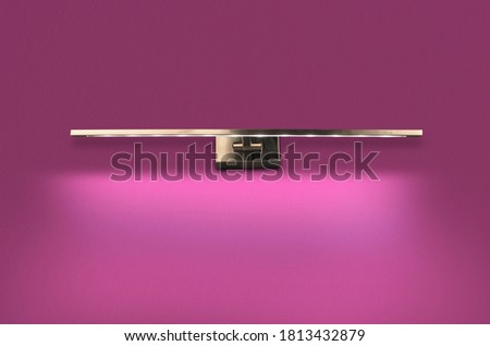 A glowing modern Metal led lamp on the pink wall.