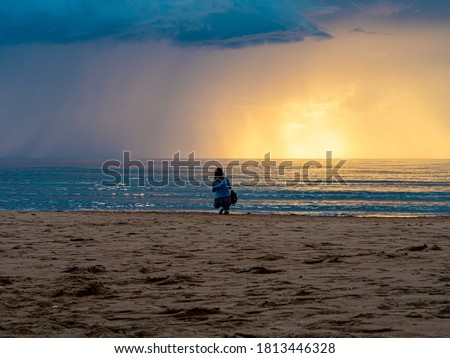 beautiful alone girl on the beach. Girl looking at stormy sea amd taking a picture with smarphone. The spectacular Storm with rain Is Coming in Estonia. Baltic sea