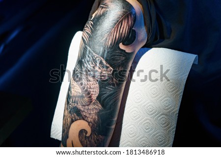 Picture of man doing black tattoo of snake for woman