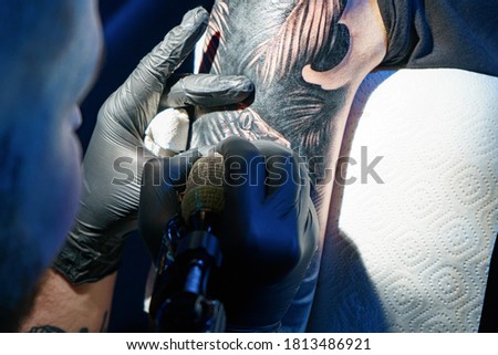 Picture of tattooist doing black tattoo of snake for woman
