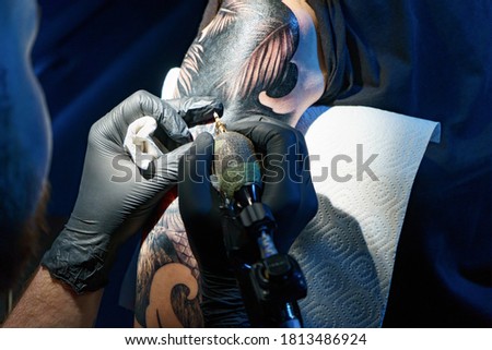 Image of man doing black tattoo of snake for woman