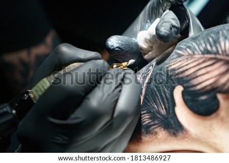 Image of master doing black tattoo of snake for woman