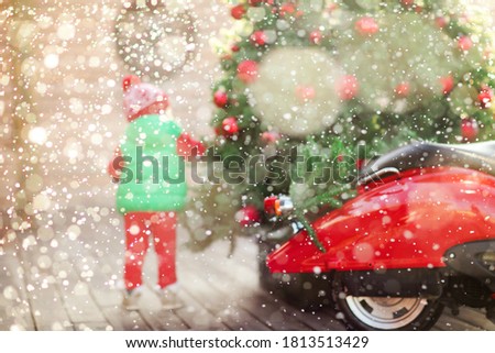 Blurry silhouette of a boy under the flying snow near the Christmas tree. Red vintage moped. High quality photo