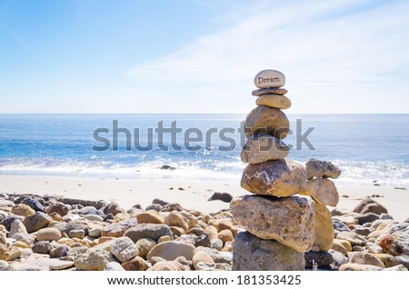 Stack of sea rocks with sign "dream" on the top balancing by Pacific ocean
