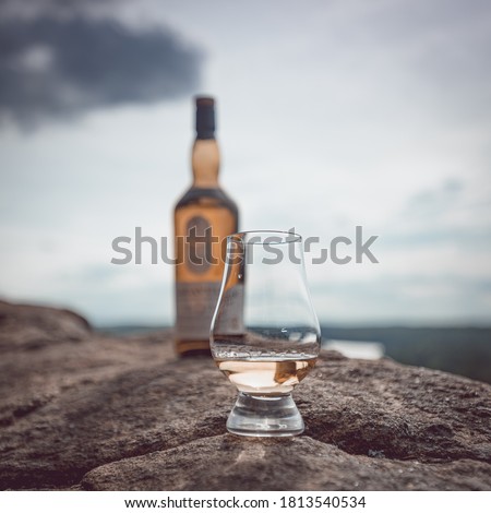 Glencairn glass with a dram of scotch whisky with a blurred scotch bottle in the background.