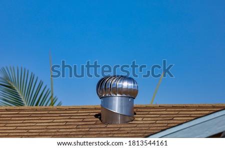 An internally braced aluminum wind turbine on top of a house's shingle roof.